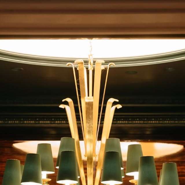 Bar 37 de l’hôtel The Woodward à Genève, lustre doré et abat-jours verts
